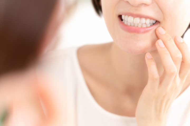 鏡で歯のチェックをする女性