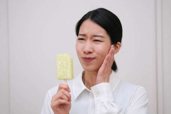 虫歯の初期症状で冷たいアイスが歯にしみる女性