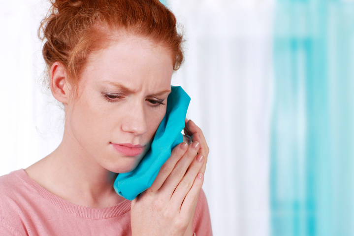 根管治療の痛みを抑えるために患部を冷やす女性