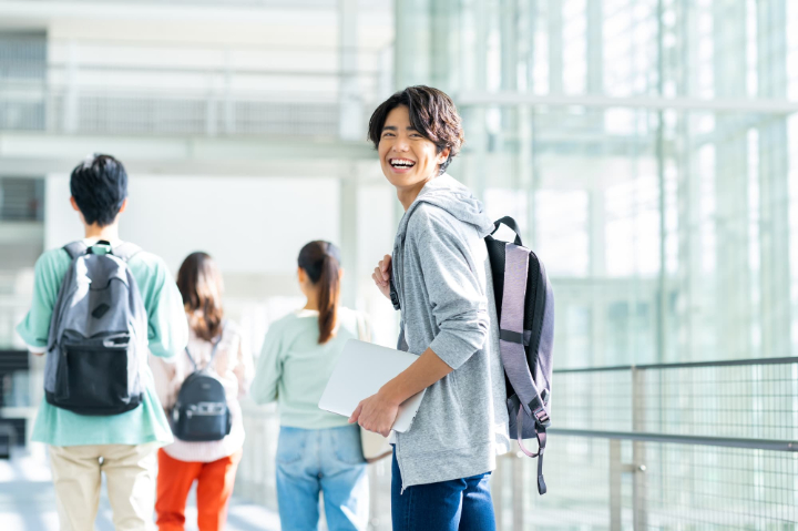 大学のキャンパスで笑顔で振り返る男性