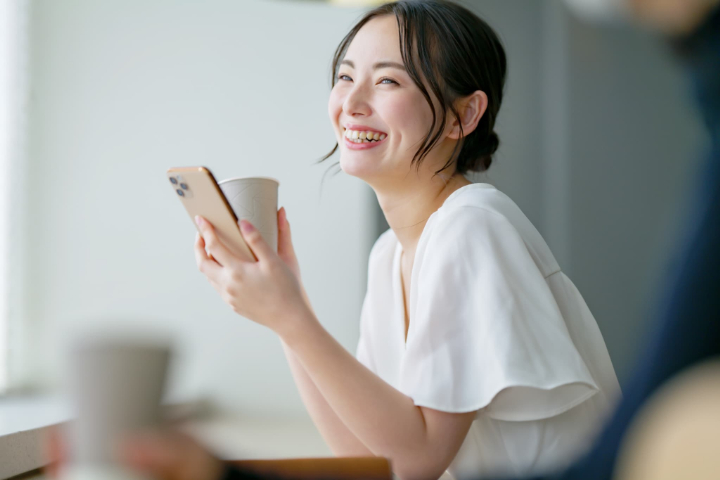 カフェでスマホを片手に寛ぐ女性