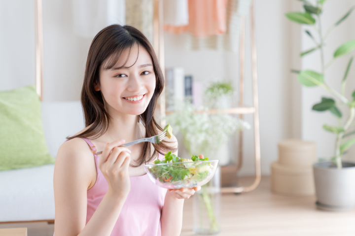 根管治療を終えた女性がサラダを食べているイメージ
