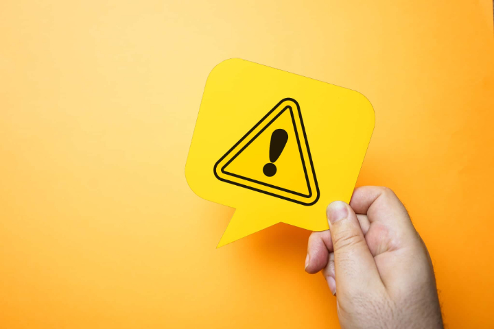 ワイヤー矯正で抜歯をするときの注意点を示すビックリマークを持った手