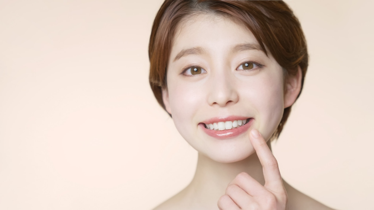 セラミックの歯で見た目が美しくなった歯を指さす笑顔の女性